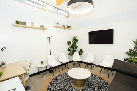 Salle d'attente lumineuse avec fauteuils blancs et plantes vertes