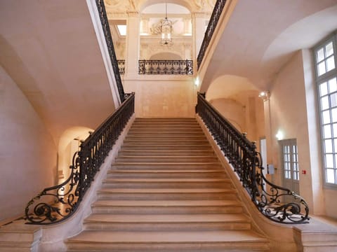 Grand escalier de pierre clair avec rampe en fer forgé dans un immeuble